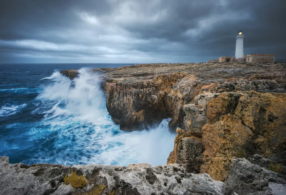 Farol firme na costa, com ondas fortes batendo nas pedras